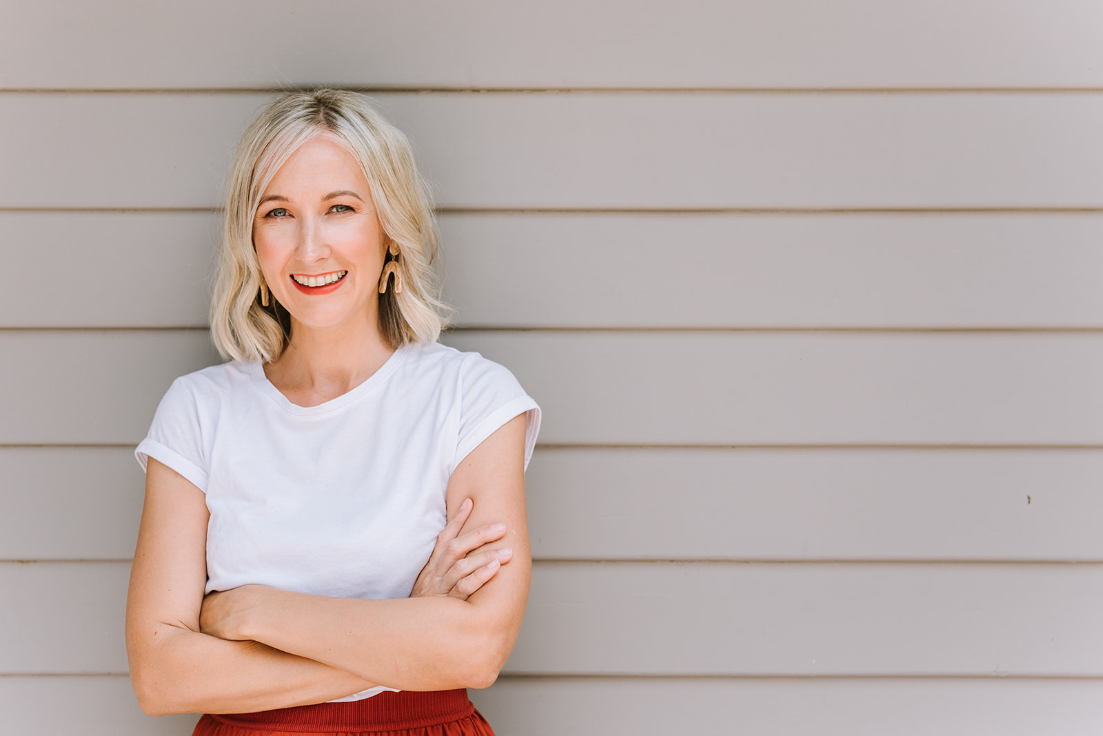 Newcastle copywriter Kerrie Brooks smiling stood against a wall with arms crossed